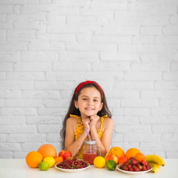 Portrait of girl with fruits over the white desk