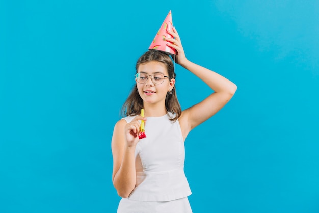 Free photo portrait of a girl with party horn standing on blue background