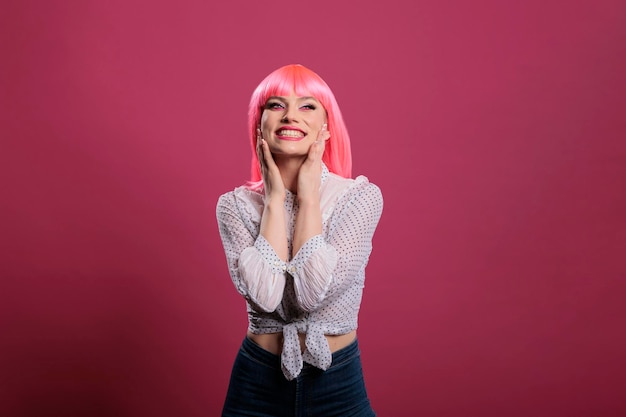 Free photo portrait of glamour model smiling and posing on camera, feeling happy and positive in studio. carefree joyful woman with pink hair wig and elegant makeup doing sensual attractive moves.