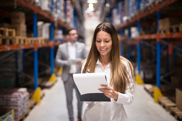 Free Photo portrait of gorgeous brunette woman manager controlling business in warehouse logistic center well dressed successful woman checking distribution while ceo walking behind her.