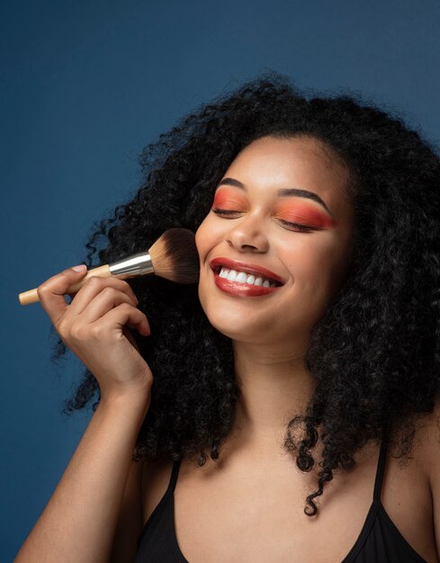 Portrait of a gorgeous woman applying make-up with a make up brush