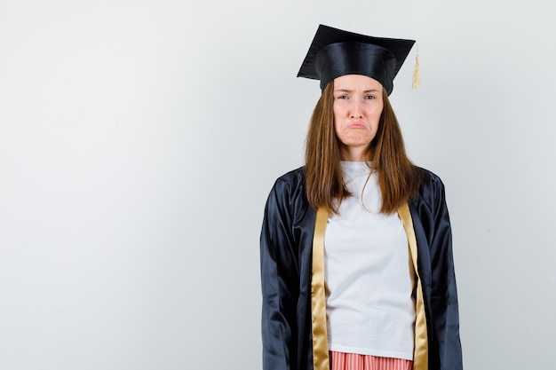 Free photo portrait of graduate woman looking at camera while frowning face, curving lips in casual clothes, uniform and looking offended front view