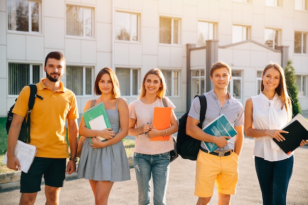 Free photo portrait of group of happy students in casual outfit with books while standing