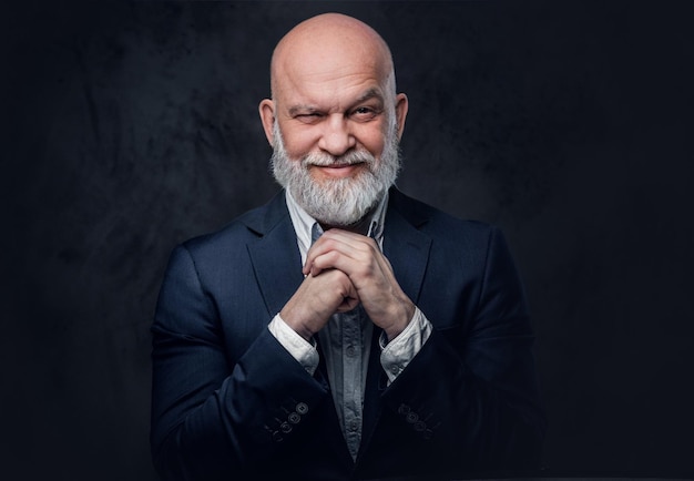 Portrait of hairless old man looking at camera against dark studio background.