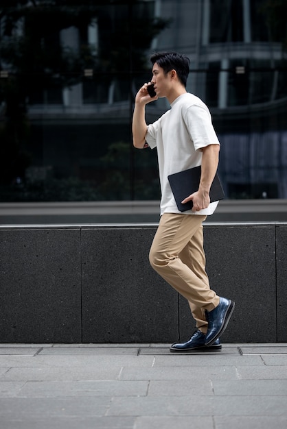 Portrait of handsome asian man using smartphone outdoors in the city