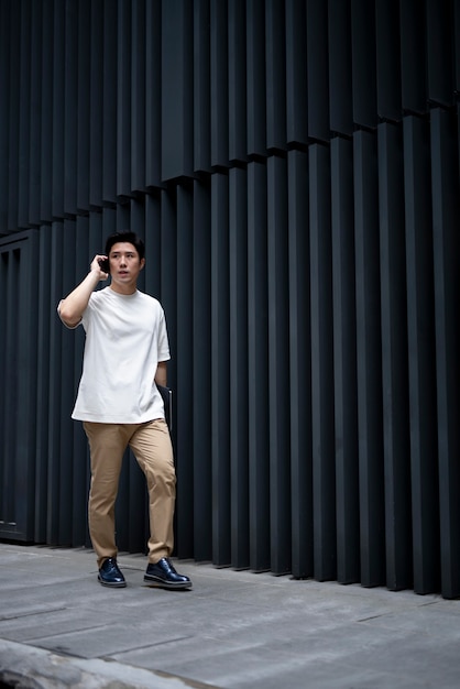 Portrait of handsome asian man using smartphone outdoors in the city