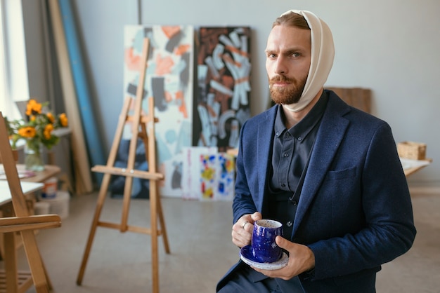 Free Photo portrait of handsome bearded man with ear bandage in an art studio