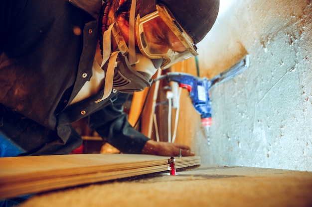 Portrait of handsome carpenter working with wooden skate at workshop