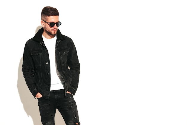 Free photo portrait of handsome confident model sexy stylish man dressed in biker leather jacket and black jeans fashion hipster male isolated on white in studio in sunglasses