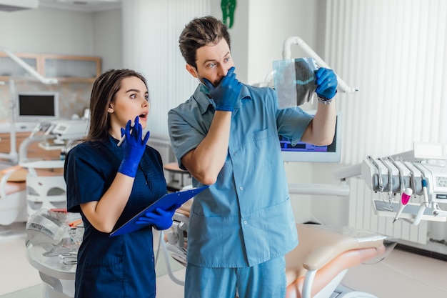 Portrait of handsome dentist standing with her colleague and holding x-ray.