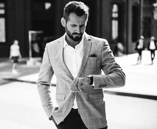 Portrait of handsome fashion businessman model dressed in elegant blue suit. Man posing on street background. Metrosexual
