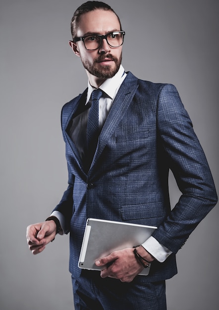 Portrait of handsome fashion businessman model dressed in elegant blue suit with glasses