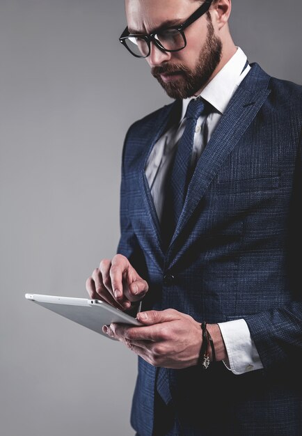 Portrait of handsome fashion businessman model dressed in elegant blue suit with glasses