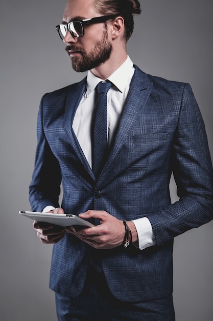 Portrait of handsome fashion businessman model dressed in elegant blue suit with glasses