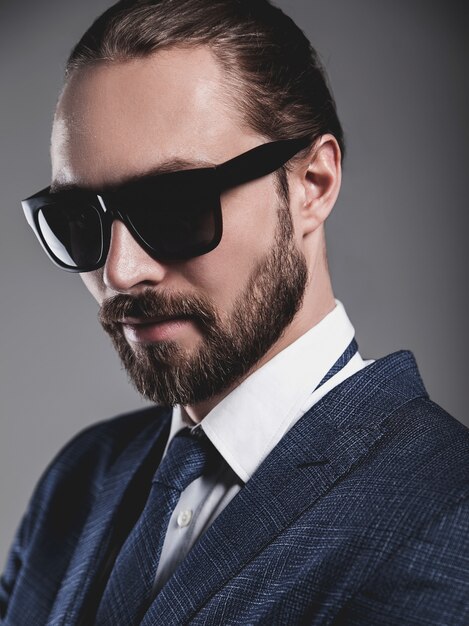 portrait of handsome fashion businessman  model dressed in elegant blue suit with sunglasses