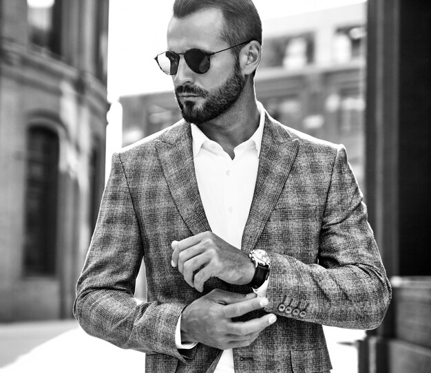 Portrait of handsome fashion businessman model dressed in elegant checkered suit posing on street