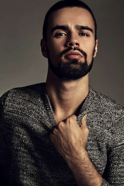 portrait of handsome fashion stylish hipster model dressed in warm sweater  posing in studio.