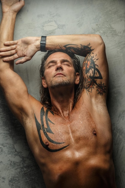 Free Photo portrait of handsome long-haired man with naked torso. isolated on gray background. tattoed male body.