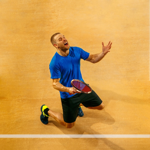 Free Photo portrait of a handsome male tennis player celebrating his success on a court wall