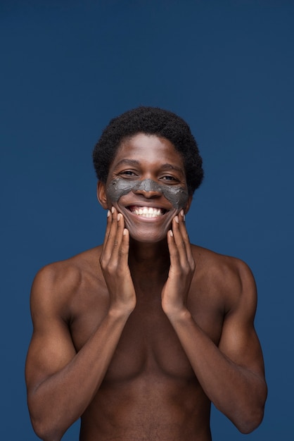 Portrait of a handsome man applying charcoal face mask