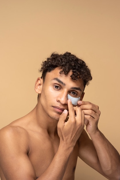 Portrait of a handsome man applying an under eye patch