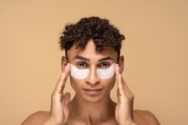 Portrait of a handsome man applying under eye patches