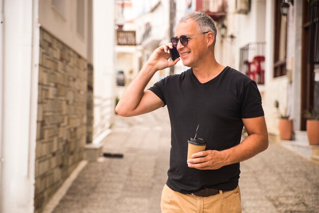 Portrait of handsome man drinking coffee and talking talking on phone