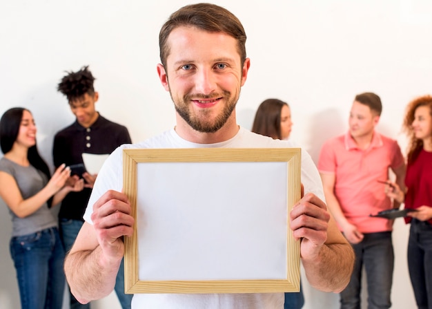 Portrait of a handsome man holding empty picture frame looking at camera