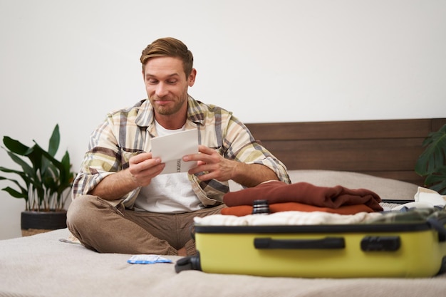 Free photo portrait of handsome man tourist looking at his holiday tickets booked vacation with travel agency