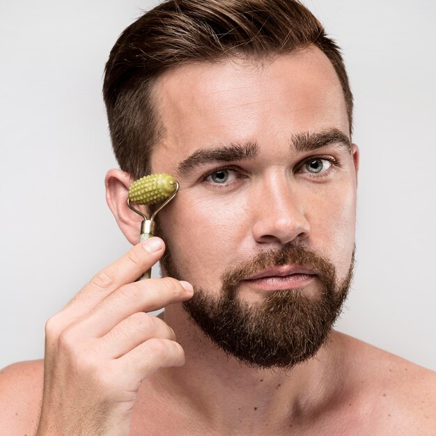 Portrait of handsome man using a face roller