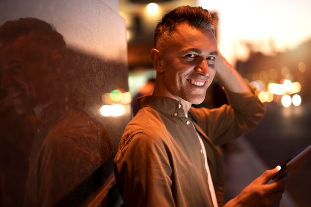 Portrait of handsome man using tablet at night in the city lights