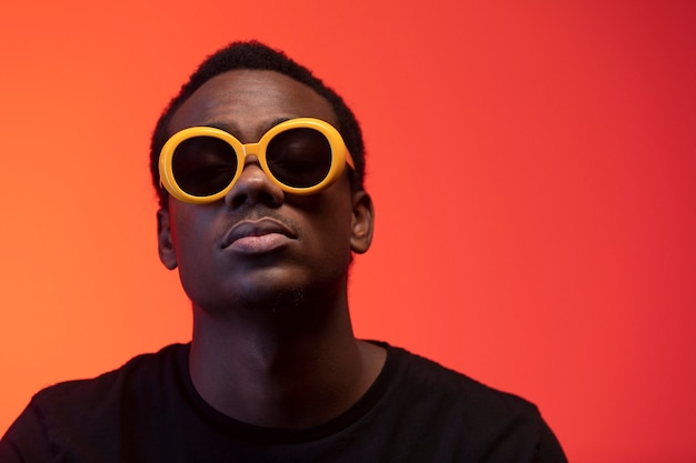 Portrait of handsome man with sunglasses over orange background