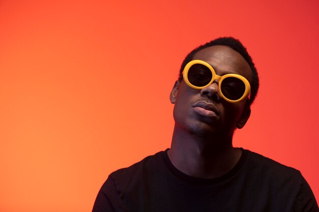 Portrait of handsome man with sunglasses over orange background