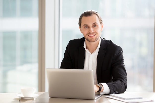 Portrait of handsome smiling businessman at work in office.