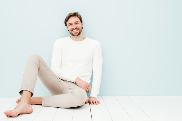 Free photo portrait of handsome smiling hipster lumbersexual businessman model wearing casual white sweater and trousers