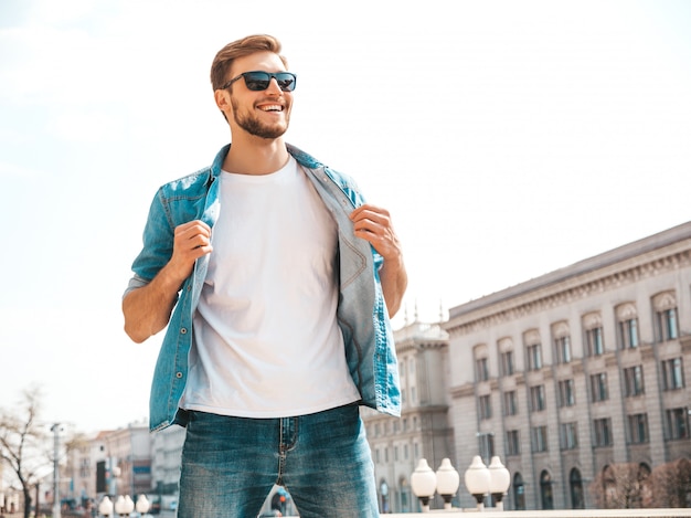 Free photo portrait of handsome smiling stylish hipster lumbersexual businessman model. man dressed in jeans jacket clothes.