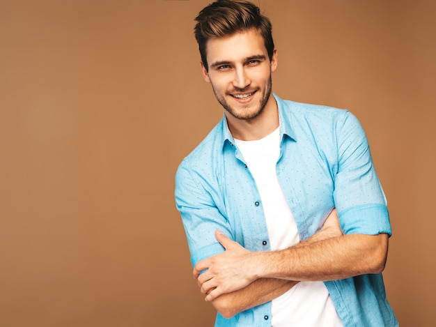 Free photo portrait of handsome smiling stylish young man model dressed in blue shirt clothes. fashion man posing. crossed arms