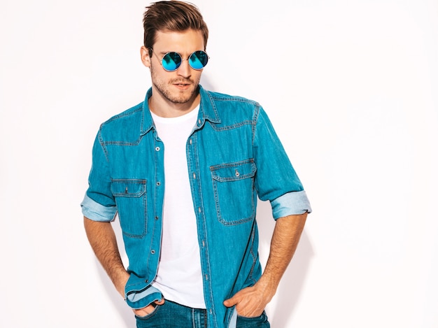 Portrait of handsome smiling stylish young man model wearing jeans clothes and sunglasses. Fashion man 