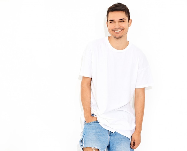 Portrait of handsome smiling young model man dressed in jeans clothes  and T-shirt posing. Touching his head