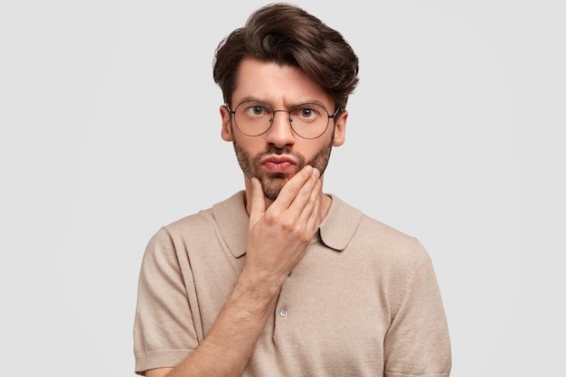 Portrait of handsome surprised bearded male looks scrupulously at camera