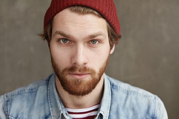 Portrait of handsome young hipster male of European appearance posing indoors