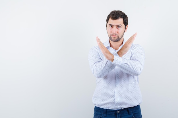 Portrait of handsome young man in white patterned shirt crossed arms and looking so serious isolated on white background