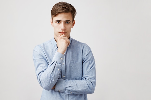 Free photo portrait of handsome young man with hand on chin, thoughtful look