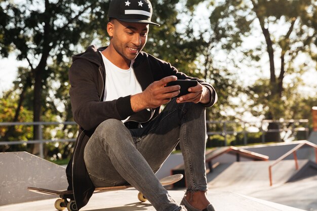 Portrait of a happy african guy using mobile phone