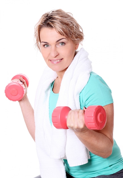 Portrait of happy aged sportswoman with dumbbells