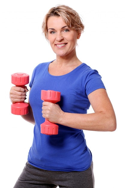 Portrait of happy aged sportswoman with dumbbells