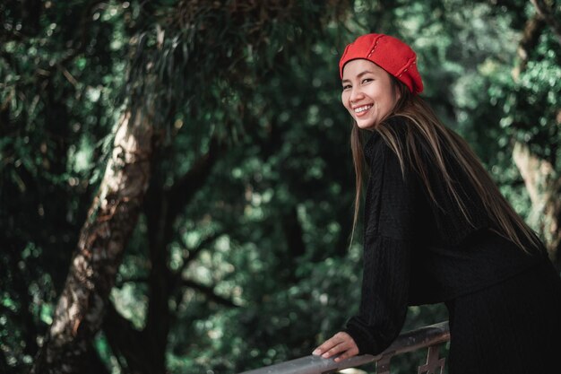 Portrait of Happy Asian young woman in winter costume at the forest with copy space Vacation and travel concept