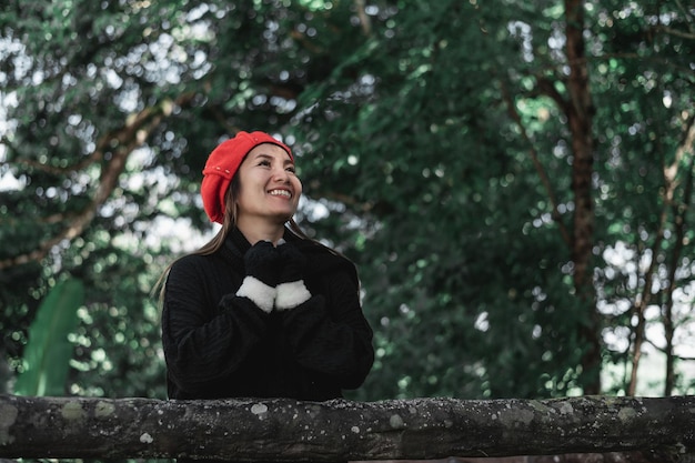 Free photo portrait of happy asian young woman in winter costume at the forest with copy space vacation and travel concept