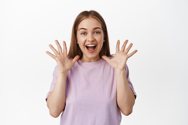 Free Photo portrait of happy beautiful girl, rejoicing, scream from joyful and positive feelings, shaking hands and telling big news, awesome announcement, standing over white background