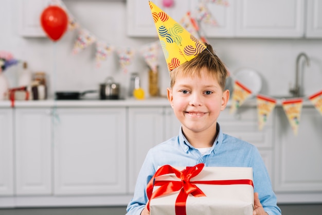 Free Photo portrait of a happy boy holding birthday gift in kitchen